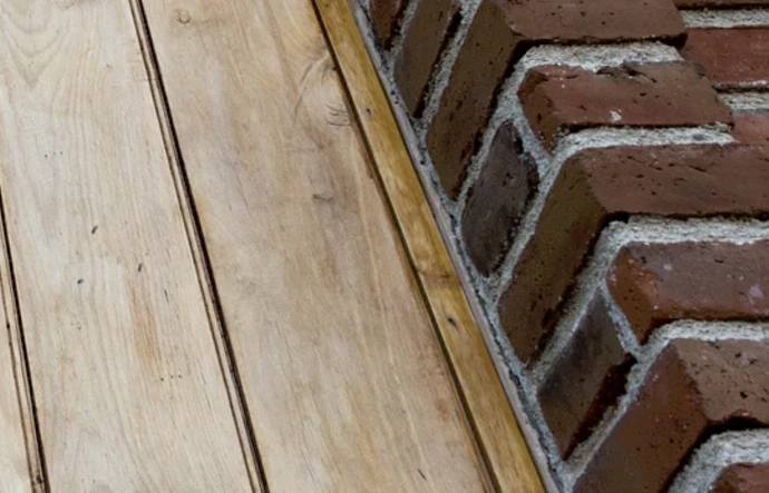 Detail zdi cihlového domu s dřevěnou podlahou.