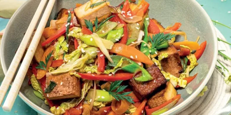 Připravený pokrm z tofu a zeleniny v misce s čínskými hůlkami.