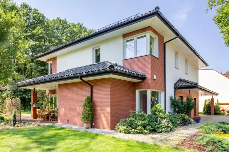 Moderní cihlový dům s zahradou v přírodním prostředí.