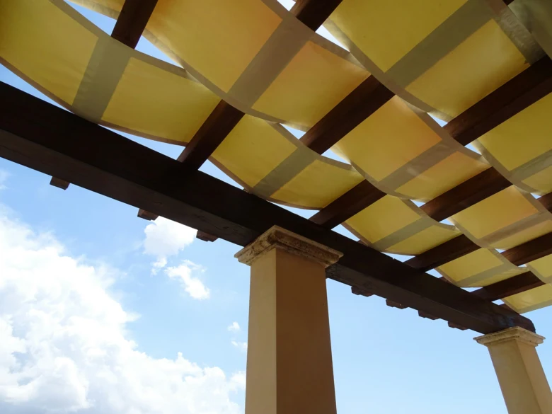 Dokončená pergola s žlutými textilními panely a dřevěnou konstrukcí