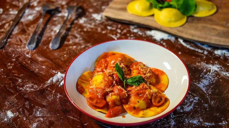 Mísa s ravioly v rajčatové omáčce na stolu.