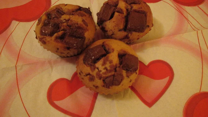 Tři čokoládové muffiny na srdcovém papíru.