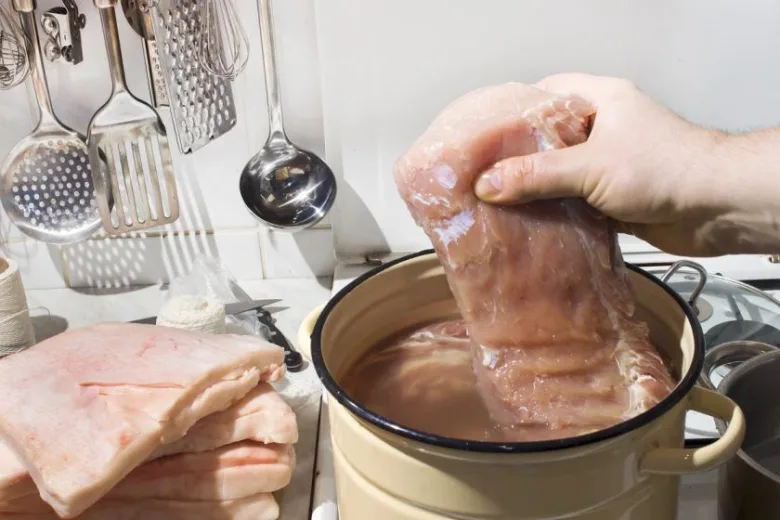 Připravování masa pro zavařování klobás v kuchyni.