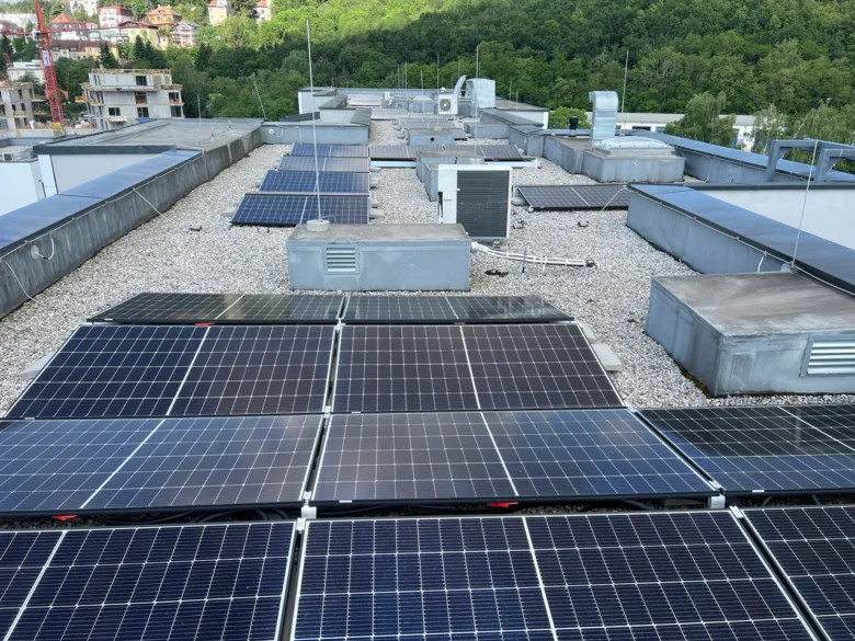 Fotovoltaické panely na střepe budovy s výhledem do přírody.