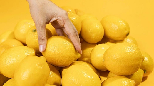 Ruka vybírá citron ze zásoby čerstvých plodů.