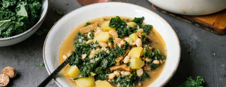 Miska s veganskou zeleninovou polévkou se špenátem a fazolí.
