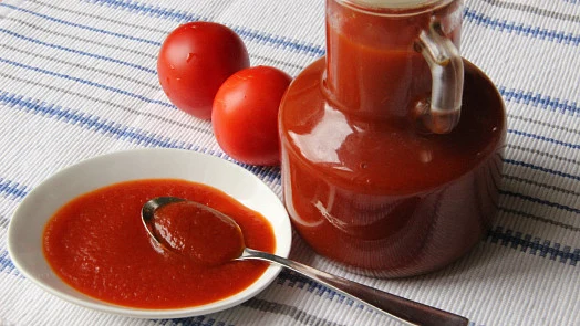 Ketchup v lahvičce s čerstvými rajčaty na ubrousku