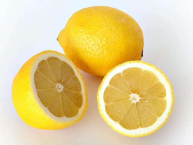 Žluté citrony, jeden celý a dva polovičky s viditelnou dužinou.