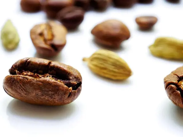 Zrnka kávy s kardamonem na bílém pozadí