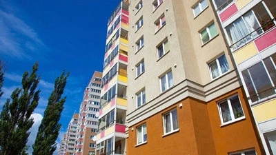 Moderní panelové domy s barevnými fasádami pod modrou oblohou.
