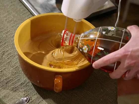 Nalévání medu do mísy při výrobě domácího likéru.