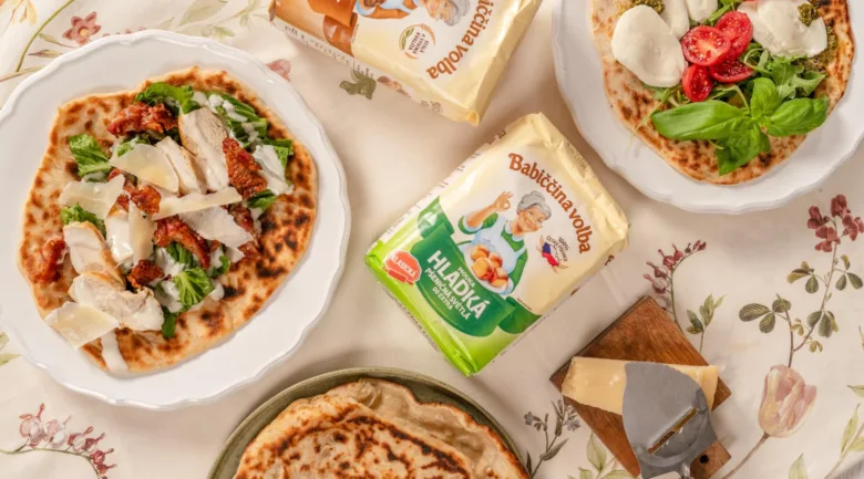 Připravené pizzové těsto s různými ingrediencemi.