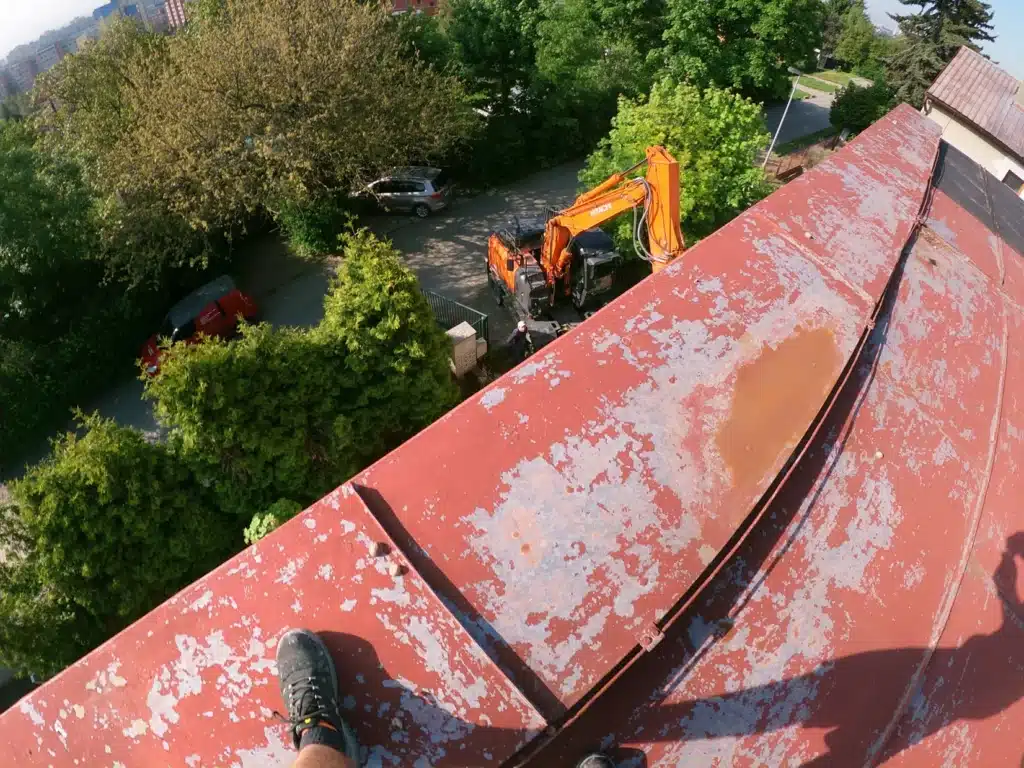 Pohled z střechy na místo demolice s výkopovou technikou.