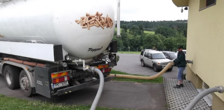 Nákladní vůz s pelety přivádí palivo do zásobníku budovy pro vytápění.