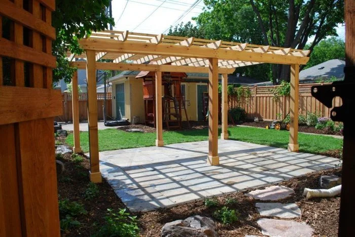 Dřevěná pergola na zahradním nádvoří s kamennou dlažbou