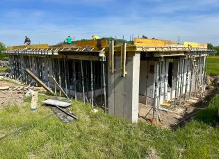 Stavba bungalovu s dřevěnými podklady na střeše a pracujícími dělníky