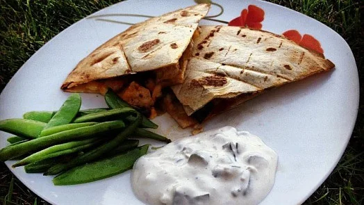 Dva domácí quesadilly s kuřetem, hráškem a omáčkou na talíři.