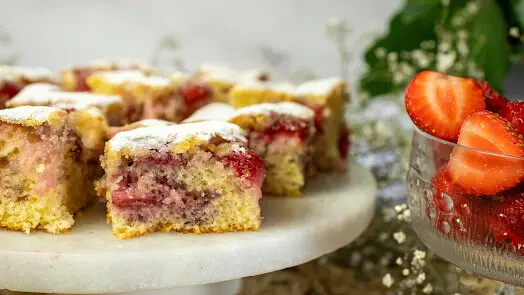 Čerstvé pečené muffiny s jahodami na mramorovém podstavci.