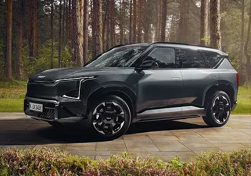Tmavý SUV automobil stojí na cestě v lese.