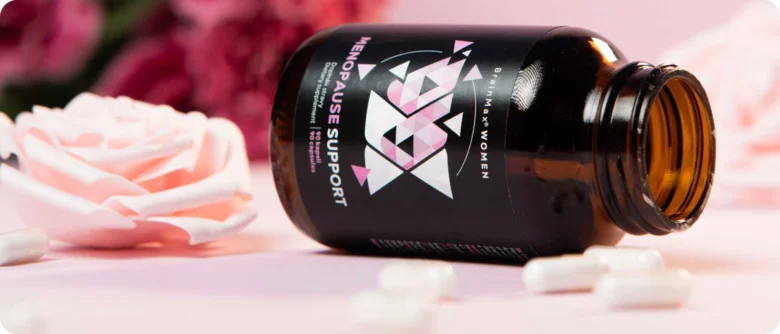 Fialová lahvička s doplňkem pro menopauzu na růžovém pozadí.