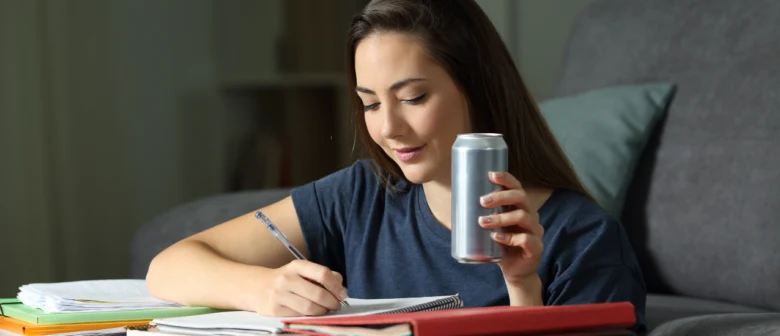 Dívka pije nápoj s taurinem při studiu.