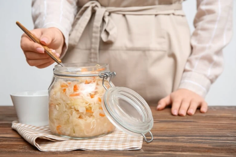 Person preparing sauerkraut in jar
