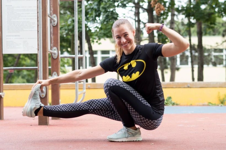 Žena cvičí venku v parku, ukazuje sílu.